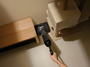 Aspirateur sans fil passé au pied d’un meuble pour chat